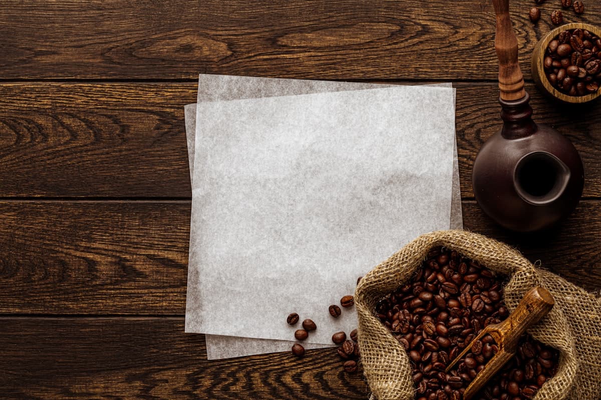 Karung biji kopi dan lembar kertas di atas meja kayu gelap, dilihat dari atas