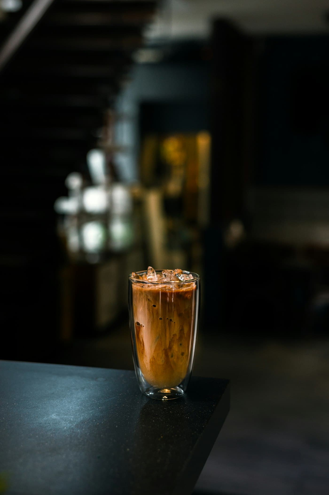 Es kopi susu dalam gelas tinggi di atas meja gelap